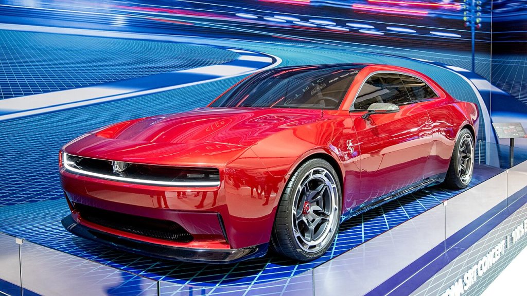  Red 2023 Dodge Charger SRT Daytona concept car displayed on illuminated platform at auto show with futuristic blue lighting