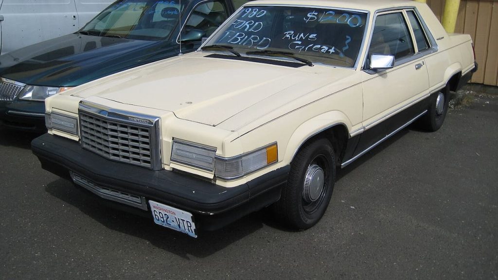 Cream-colored 1980 Ford Thunderbird with for-sale windshield sign and Washington state license plate in parking lot