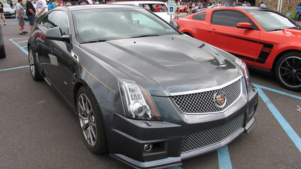 Gray Cadillac CTS-V with mesh grille and sporty wheels parked at car show next to red vehicle