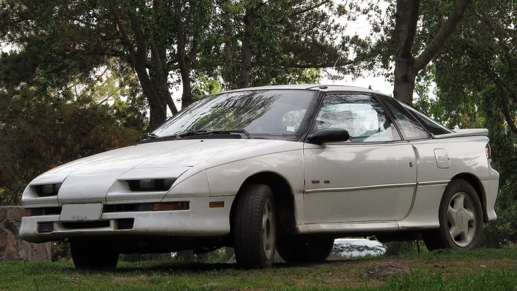 White Geo Storm GSi parked under trees in wooded area on grass and dirt