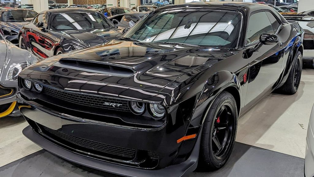 Black 2018 Dodge Challenger SRT Demon muscle car with widebody kit and aggressive styling displayed in indoor automotive showroom