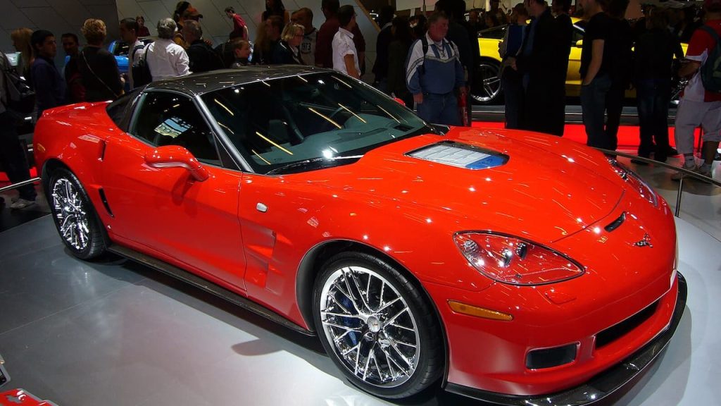 Red Chevrolet Corvette ZR1 display at auto show with crowd of visitors viewing the vehicle