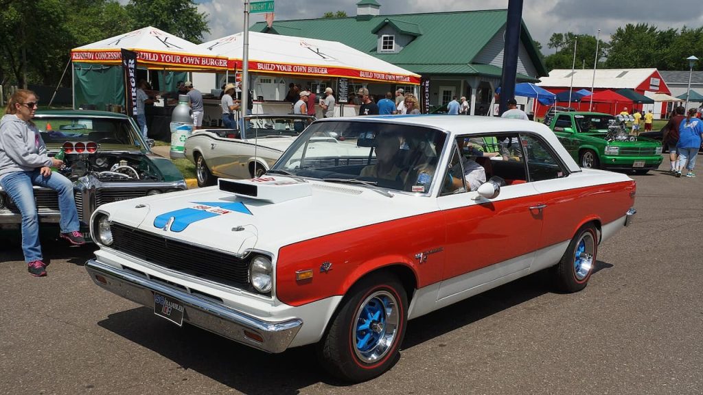 A white and red 1969 AMC Hurst SC/Rambler classic muscle car displayed at an outdoor car show event