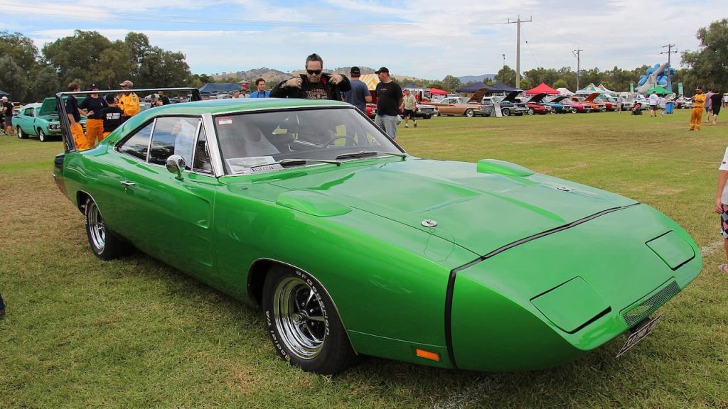 Bright green Dodge Charger Daytona with distinctive aerodynamic nose cone displayed on grass at outdoor car show