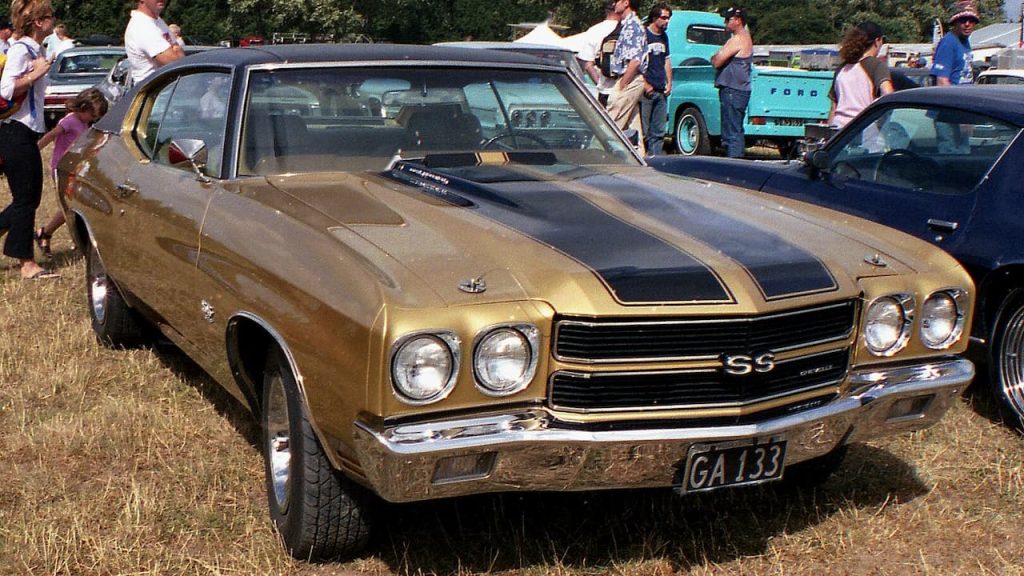 Gold 1970 Chevelle SS with black racing stripes displayed at outdoor car show, license plate GA 133 visible