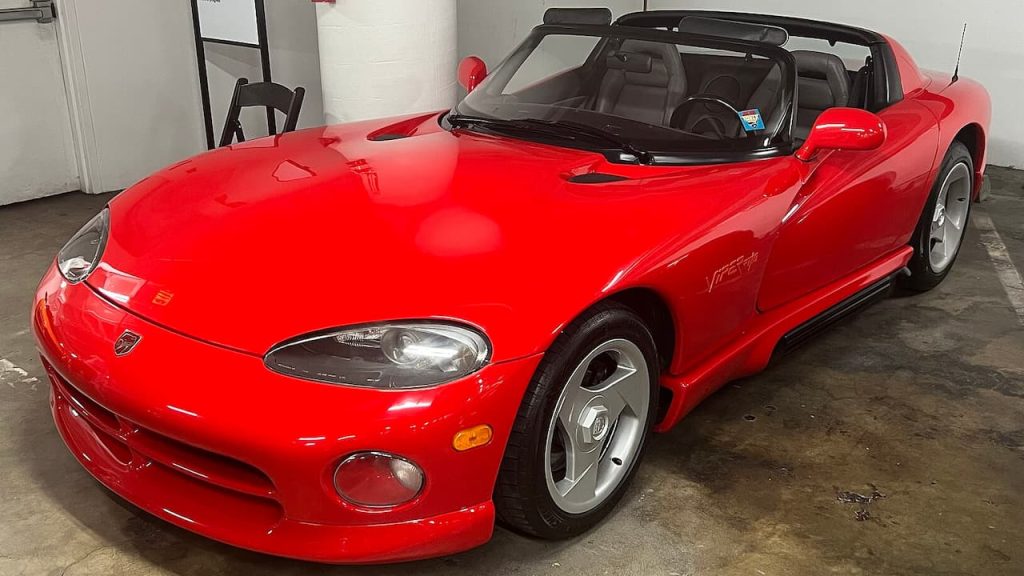 Bright red 1992 Dodge Viper convertible sports car with black interior parked in concrete garage with white walls