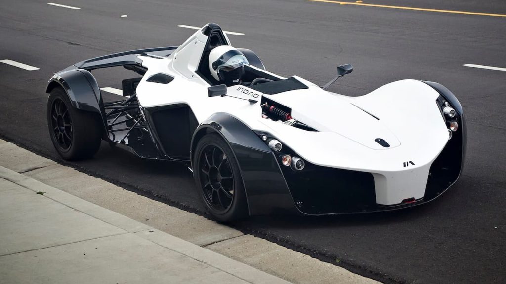 White and black BAC Mono single-seat race car with exposed suspension and open cockpit parked on asphalt road