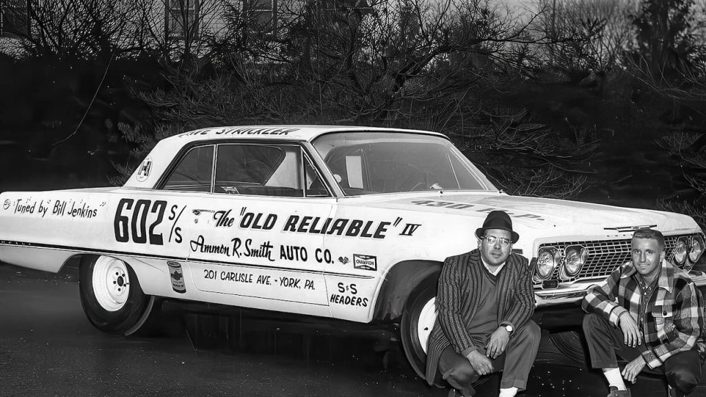 Black and white image of a 1963 Chevrolet Z11 drag car with two men crouched beside it, posing for a photo