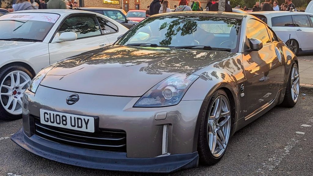 Modified silver Nissan 350Z with lowered suspension and UK license plate "GU08 UDY" at car meet