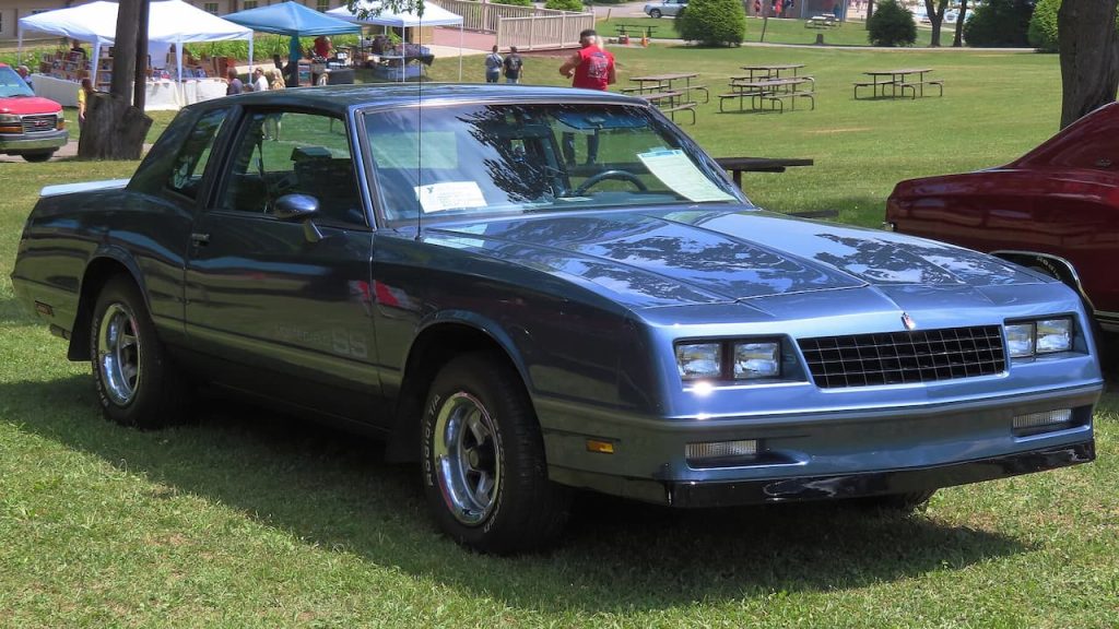 1984 Chevrolet Monte Carlo SS displayed at outdoor car show with spectators and other classic vehicles in background