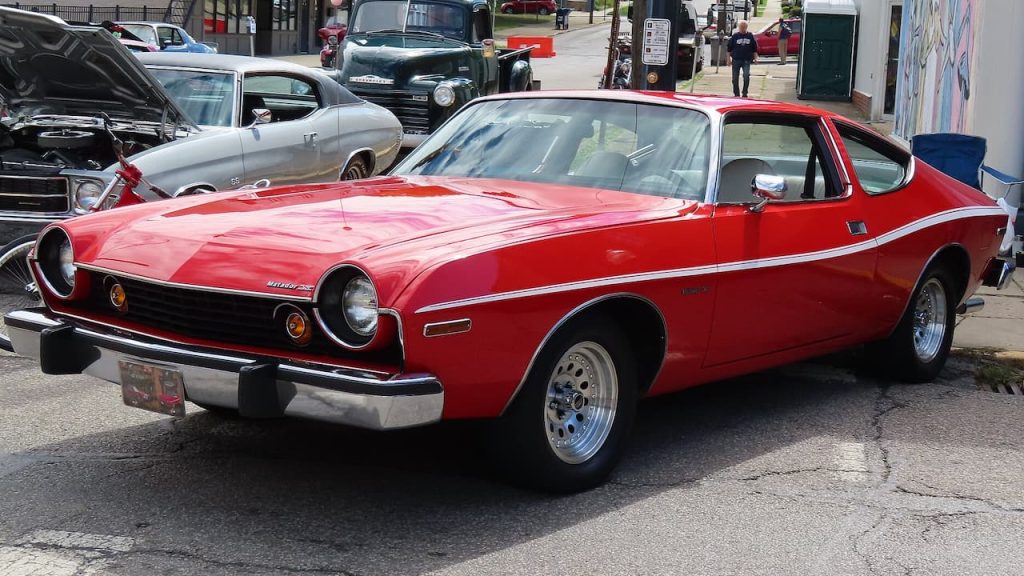 Red 1975 AMC Matador X with black grille and chrome wheels at classic car show gathering