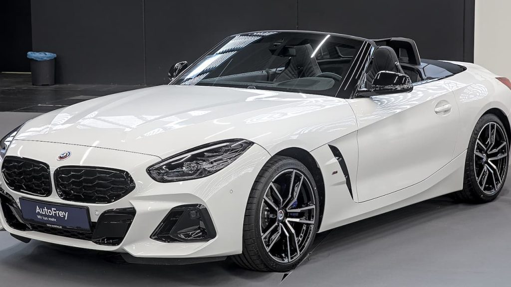  White 2024 BMW Z4 M40i convertible roadster with black soft top displayed in modern automotive showroom setting