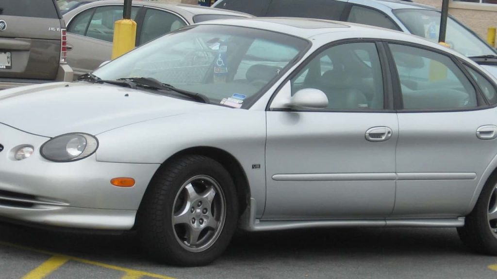 Silver first-generation Ford Taurus SHO sedan parked in lot, showing distinctive side profile with alloy wheels and SHO badging