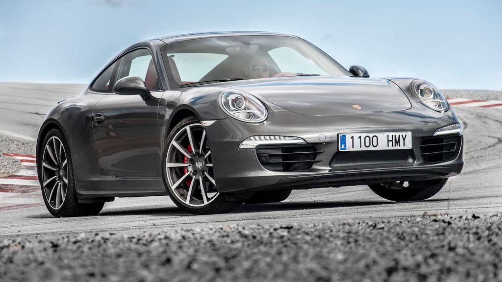 Gray Porsche 911 Carrera sports car with European license plate positioned on race track with red curbing