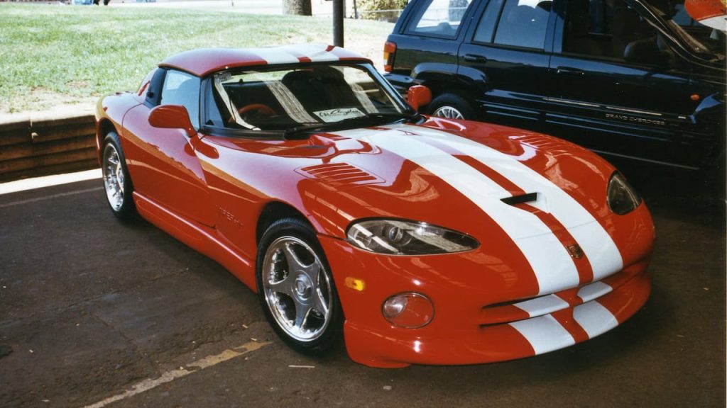 Red Dodge Viper RT/10 convertible with white racing stripes and chrome wheels parked at outdoor car event
