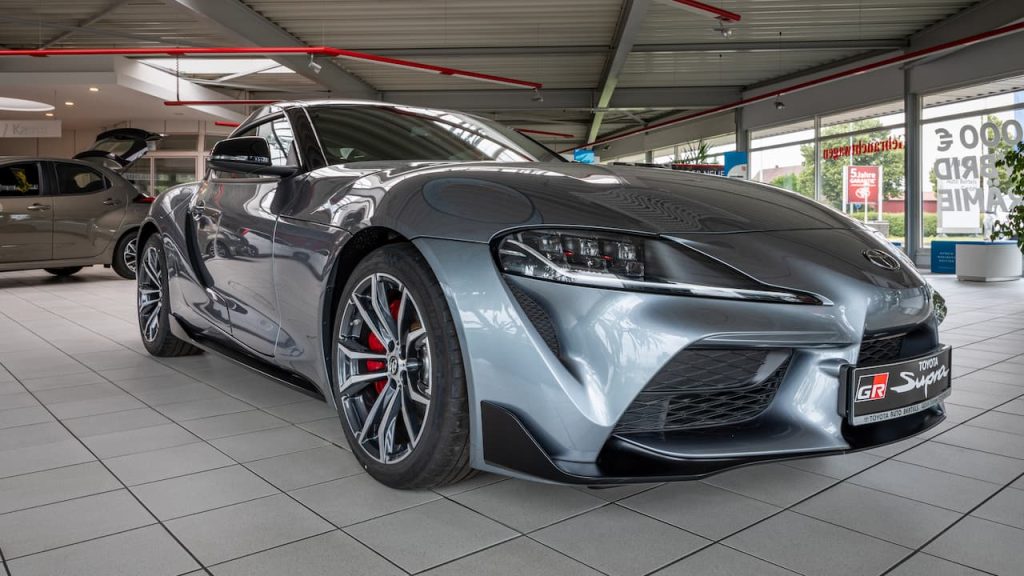  Gray Toyota GR Supra sports car displayed in modern dealership showroom with tiled floors and glass windows