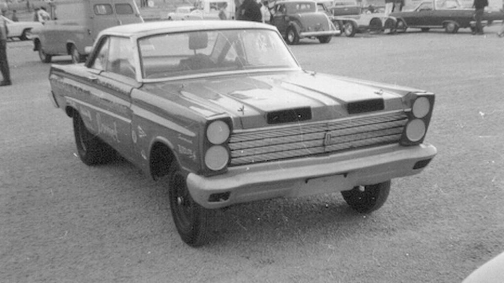 Black and white photo of a modified vintage 427 Mercury SOHC Comet drag car parked in a lot with other classic vehicles