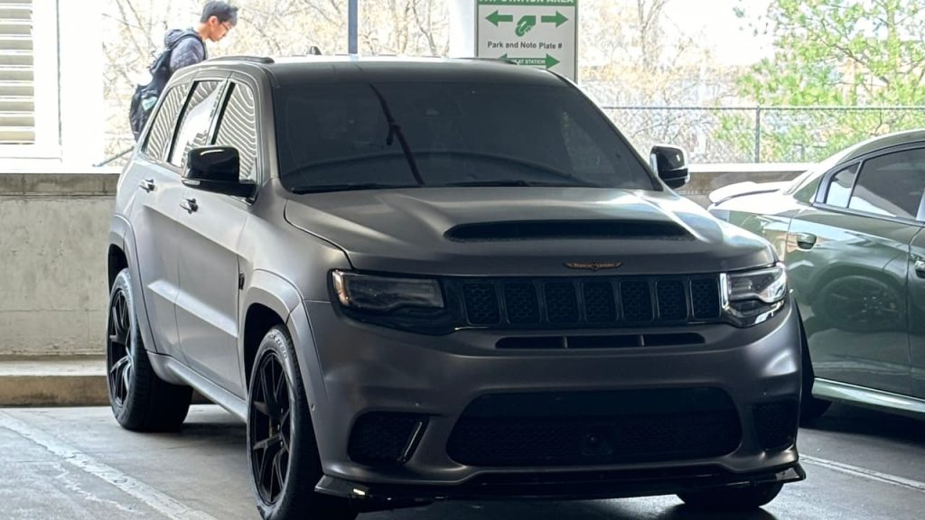 Gray 2024 Jeep Grand Cherokee Trackhawk parked in concrete garage with dark tinted windows, black wheels, and aggressive front styling