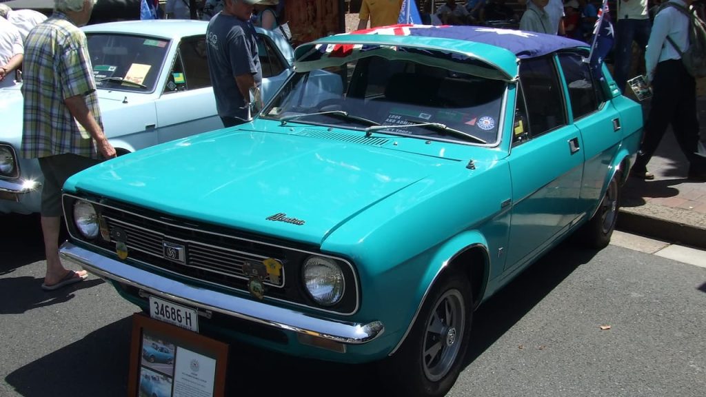 Turquoise Morris Marina with license plate 34686-H displayed at outdoor car show with spectators and other classic vehicles