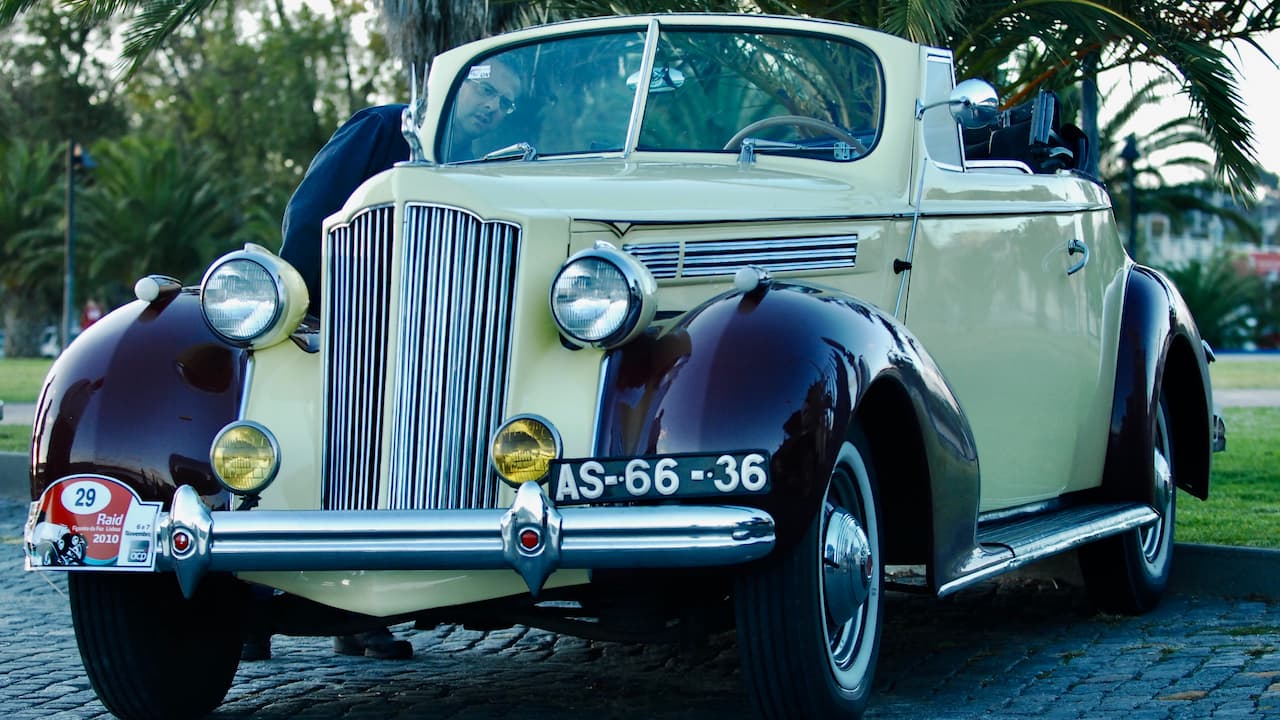 Vintage 1939 Plymouth Sedan Rare Street Rod with cream upper body, burgundy fenders, Portuguese license plate AS-66-36, parked on cobblestones