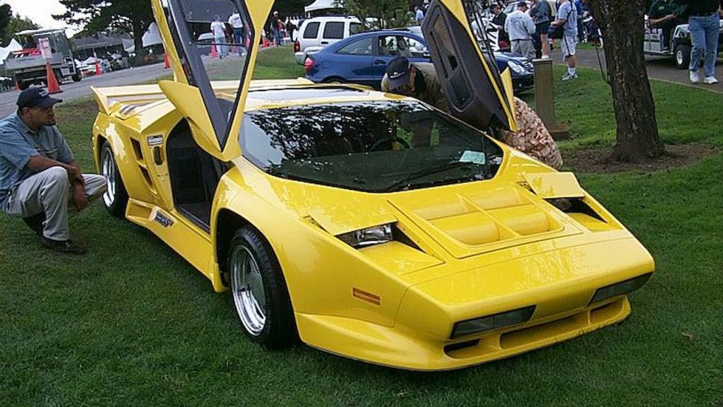 Yellow Vector W8 supercar with scissor doors open displayed on grass at car show event