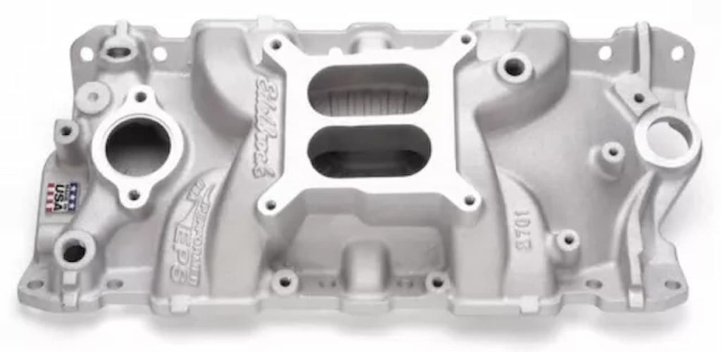 Edelbrock aluminum intake manifold with dual-plane design, carburetor mounting flange, and water jacket passages on white background