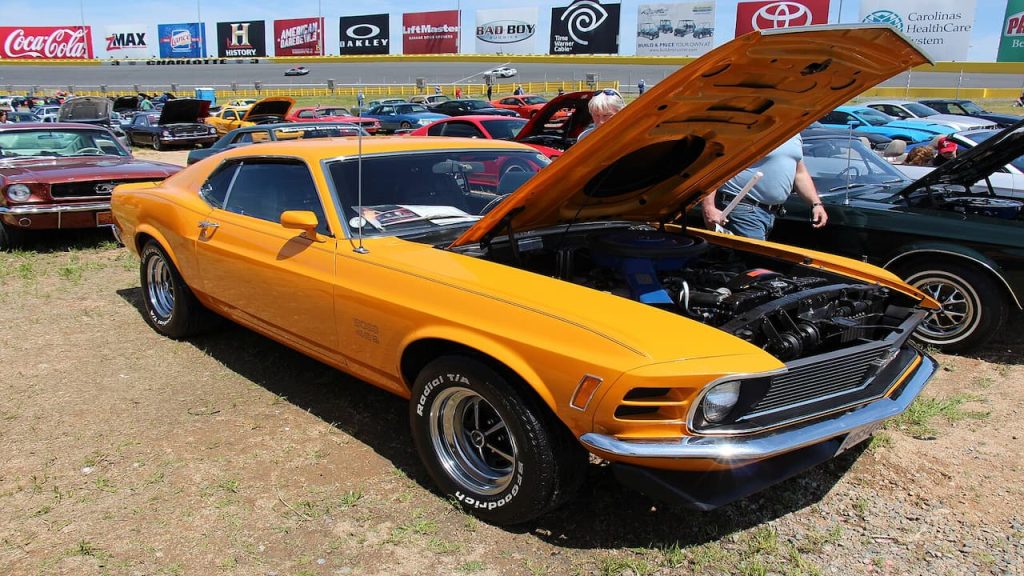 Bright orange 1970 Ford Mustang Boss 429 with open hood at classic car show displaying engine compartment