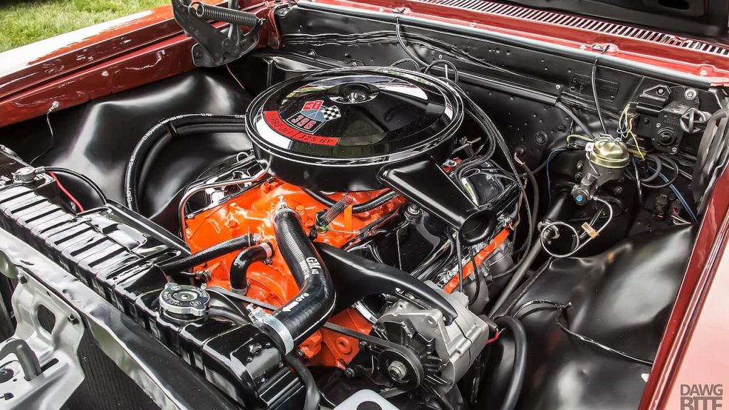 Chevrolet 396 Big Block engine bay with orange block, black air cleaner, chrome details, and various hoses in restored condition
