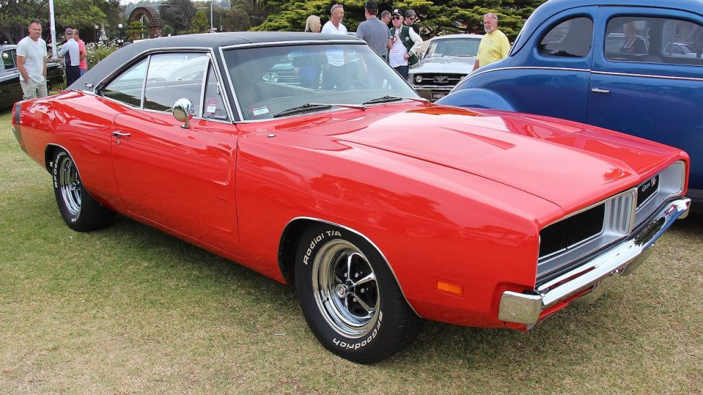 Bright red 1969 Dodge Charger R/T 426 HEMI with black vinyl roof displayed at outdoor classic car show event