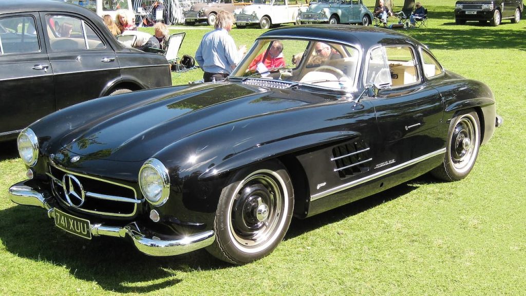 Black Mercedes-Benz 300SL Gullwing with registration 74XUU at classic car show on grass with spectators and vintage cars